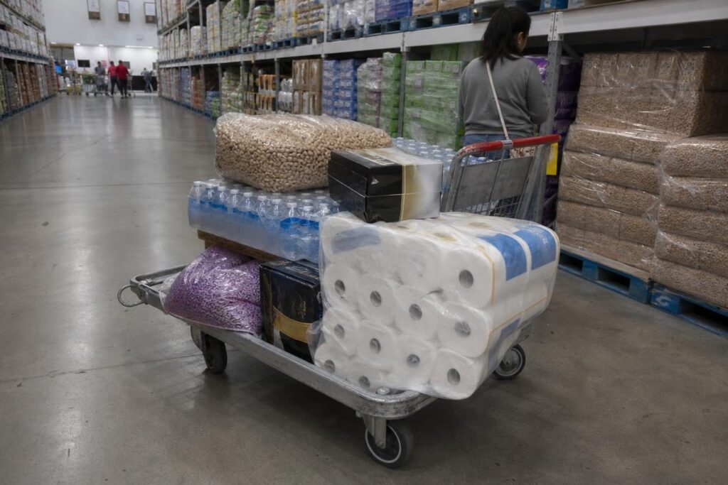 A warehouse club cart piled with bulk paper towels, water, and nuts showing what to buy at Costco